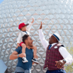 Un membre de la distribution en costume de guide touristique VIP félicitant un enfant et son père devant le vaisseau spatial Terre à EPCOT